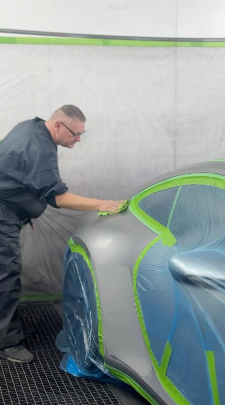 Lackierer bereitet ein abgeklebtes Fahrzeug in der Kabine vor