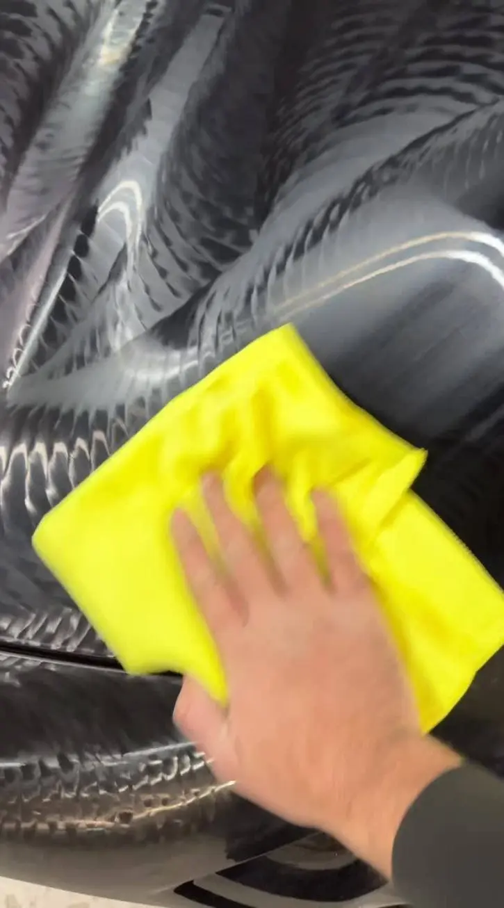 Hand mit Poliertuch auf frisch poliertem schwarzem Lack